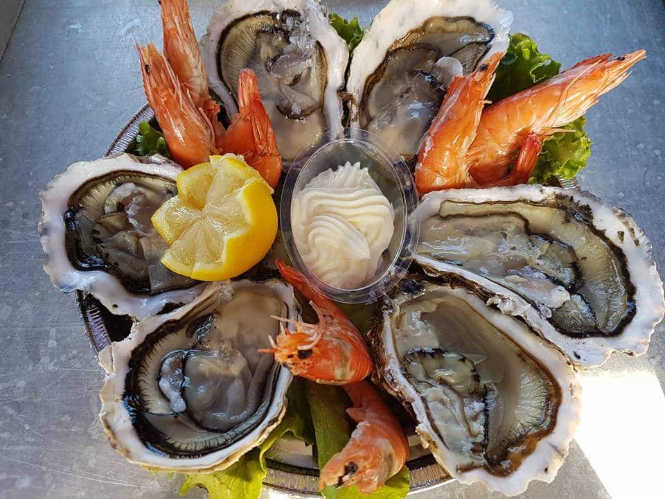Plateau de fruits de mer frais: six huîtres crues et crevettes roses, servis sur lit de laitue avec quartier de citron et sauce mayo.